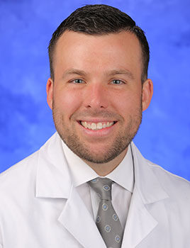 Photo of Christopher Weller, MD, pictured wearing white medical coat
