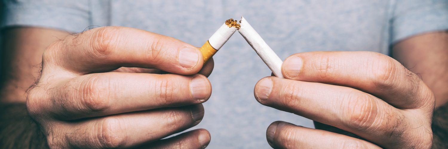 Hands holding a broken cigarette.
