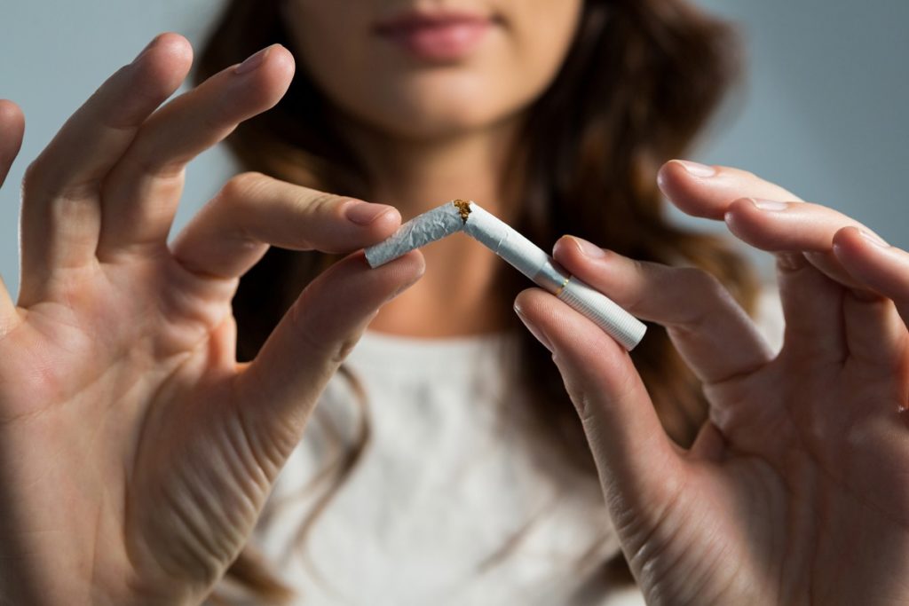 妇女破碎的香烟反对白色背景