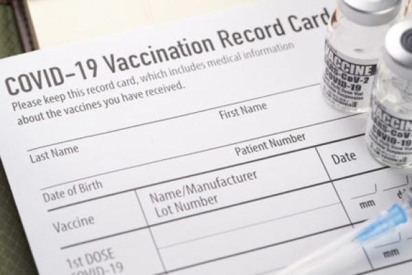 Covid-19 vaccination record card with vials and syringe.