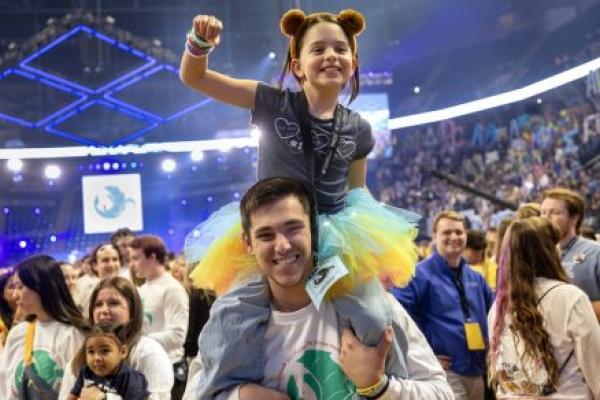 A child wearing a tutu sits on the shoulders of a college student, celebrating at THON.