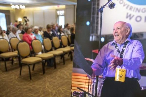 People sit in chairs facing the front of a conference room at the Hershey Lodge. A poster of Charles Millard, co-founder of Four Diamonds, is on the right.