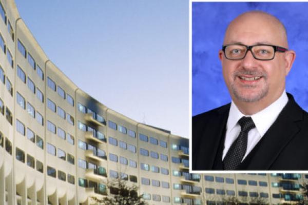 A head and shoulders professional portrait of Behzad Soleimani against a background image of Penn State College of Medicine.