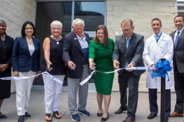 A group of people cut a ribbon in front of an interfaith chapel