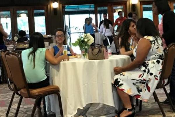 Several employees seated and talking at round table during semi-formal gathering.