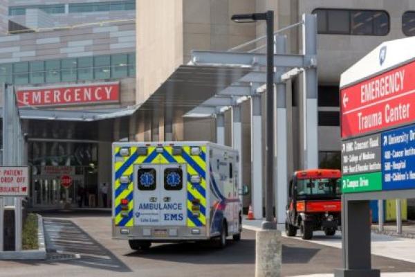 A Life Lion EMS ambulance sits in front of the Hershey Medical Center Emergency Department. A golf cart is on the sidewalk. A sign with the words: Emergency, Trauma Center, is on the right.