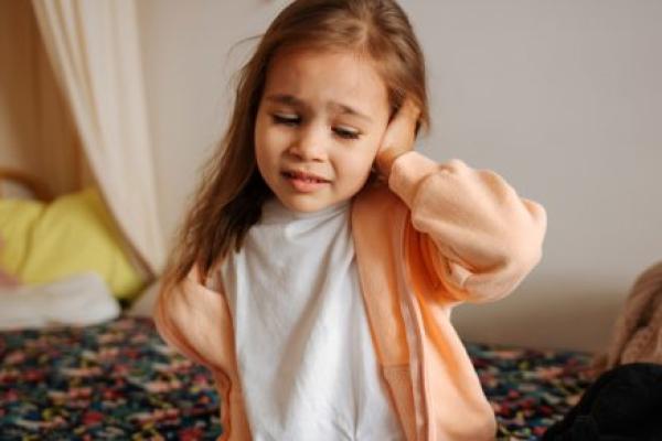 A young girl with an earache holds her ear.