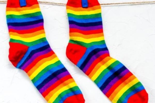 Close-up of pair of rainbow-colored socks hanging from clothesline.